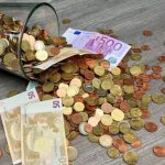 Capital - Coins and Banknotes Scattered on Gray Wooden Surface