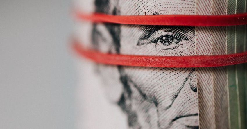 Rate - Closeup of rolled United States five dollar bills tightened with red rubber band